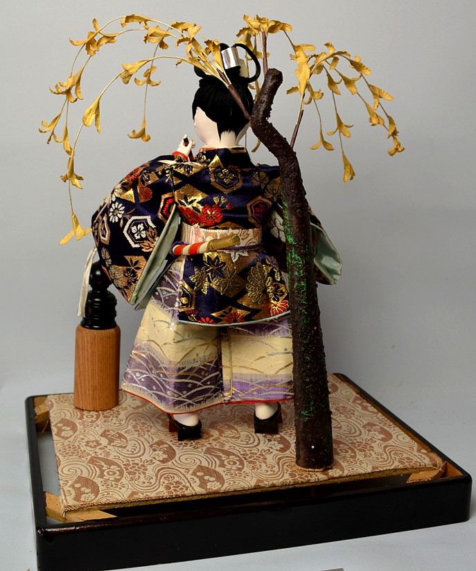 Japanese doll of Ushiwaka with flute in his hands standing under willow tree
